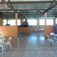 Salão de festas com churrasqueiras, mesas, cadeiras, freezers, fogão industrial, brinquedos, piscina