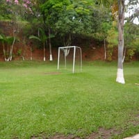 Campo gramado em frente ao salão de festas e piscinas.