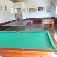 Salão de jogos com sinuca, pebolim, ping pong, mesa de carteado, mesa infantil  e lavabo.