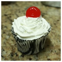 CupCake de chocolate com recheio de ganache com cereja e cobertura de chantilly.
