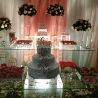 decoração mesa de vidro com arranjos, bolo cenográfico e doces finos