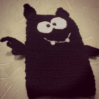 Capinha de celular feita de crochê com linha de algodão e um botão na parte posterior.
Pode ser