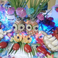 Mesa decorada com esculturas em frutas e e luzes.