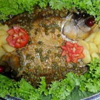 Peixe assado e recheado com risoto de camarão, coberto por alcaparas